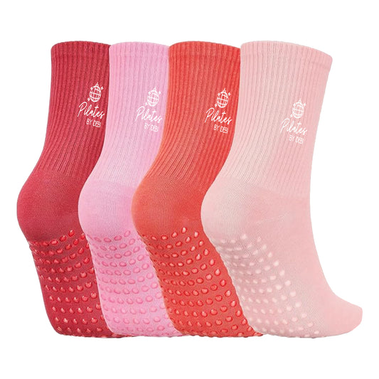 Four pairs of red and pink socks with textured soles and white Pilates by Debi logo on a white background.